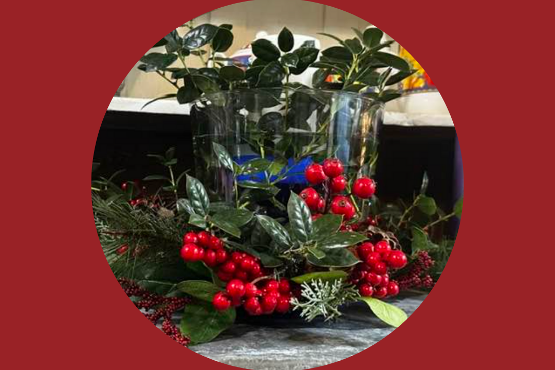 Glass vase with greenery and red berries.
